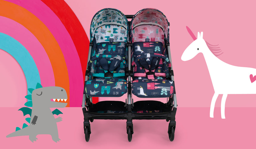 pink and blue cosatto woosh double stroller with unicorn and dinosaur rainbow background